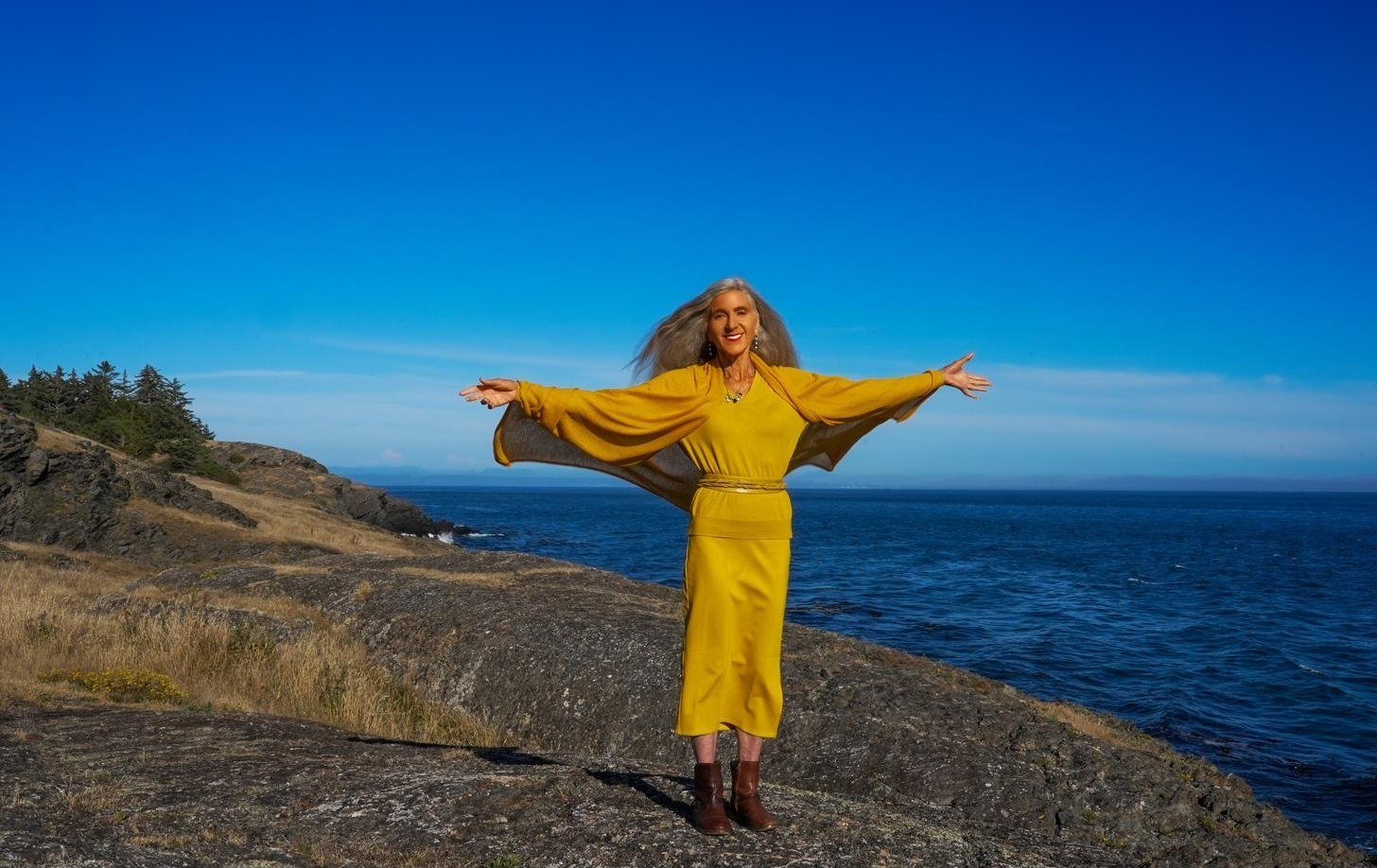 Iana Lahi standing with arms open by the sea